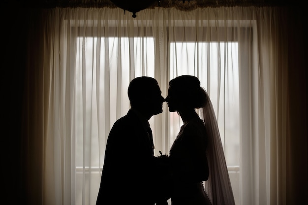 Siluetas de los novios en el fondo de una ventana.