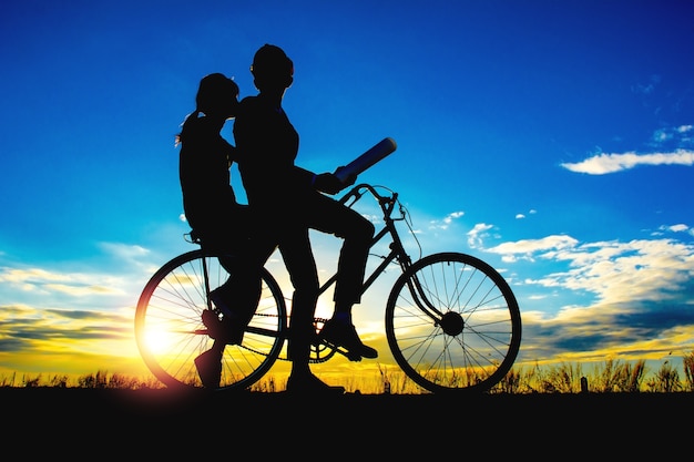 Siluetas parejas y bicicleta en el cielo del atardecer, concepto de parejas.