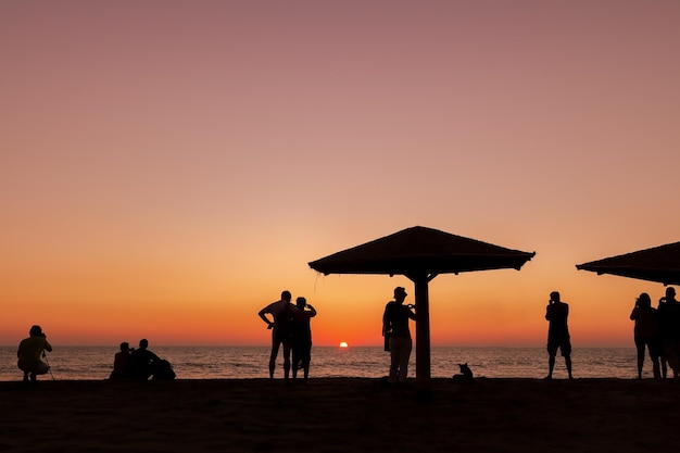 Siluetas de personas al atardecer. La gente se encuentra con la puesta de sol.