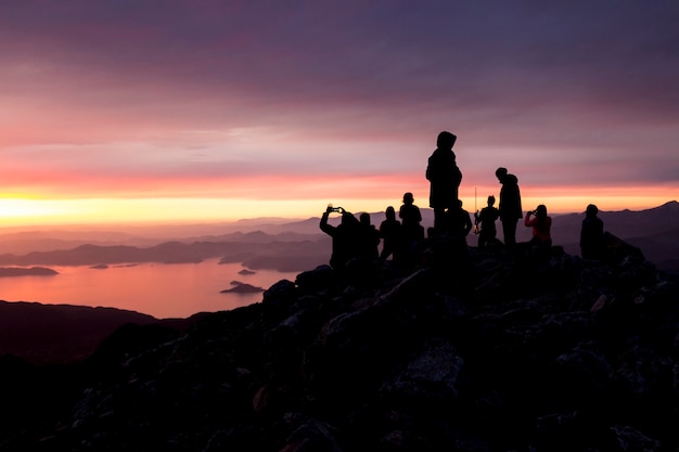 Siluetas de personas en la cima de una montaña