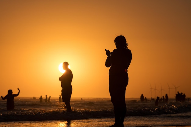 Siluetas de personas en un colorido atardecer en la playa