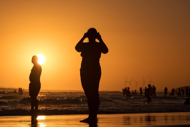 Siluetas de personas en un colorido atardecer en la playa