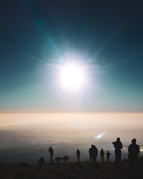 Siluetas de personas contra el sol brillante durante la puesta de sol