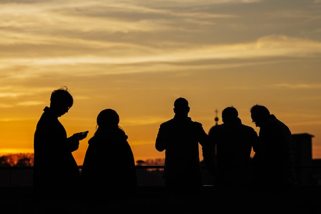 Siluetas de personas disfrutando de la puesta de sol en Florencia, Italia. Vista trasera.