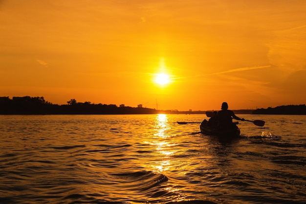 Siluetas de personas en kayak al atardecer Pareja joven está navegando en el río