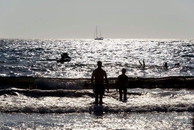 Foto siluetas de personas en la playa contra el cielo