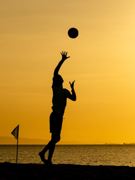 Siluetas de voleibol de playa al atardecer amarillo