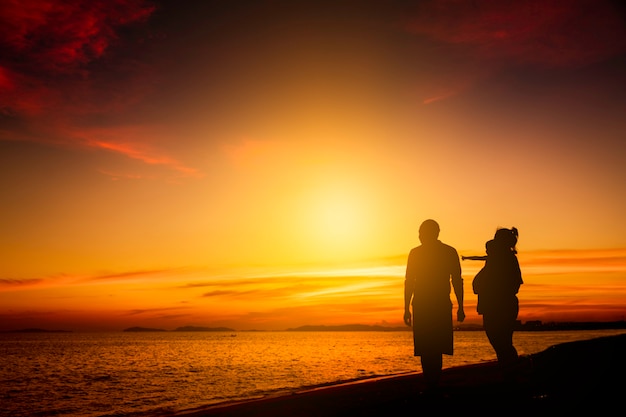 Siluetee a la familia feliz en la playa en salida del sol o puesta del sol. libertad vida y concepto de bienestar