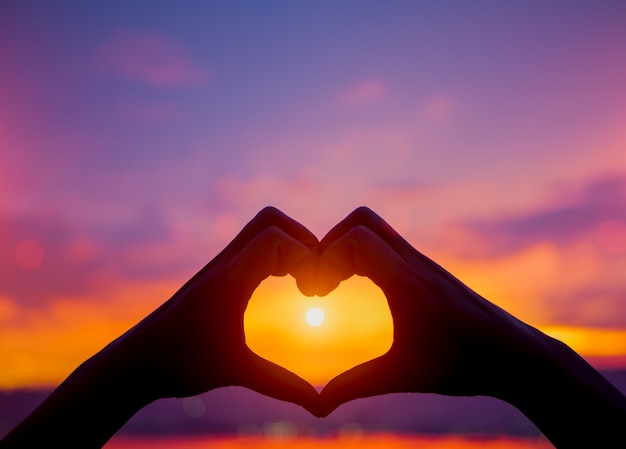 Foto siluetee las manos de la mujer para ser forma del corazón en fondo de la puesta del sol. amor, día de san valentín c