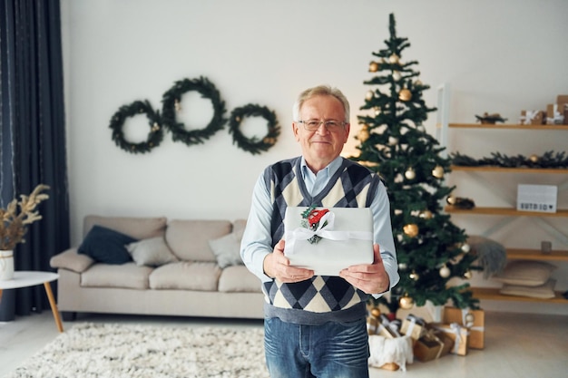 Silvester feiern und in der Nähe des Weihnachtsbaums stehen Älterer Mann in schöner Kleidung ist zu Hause