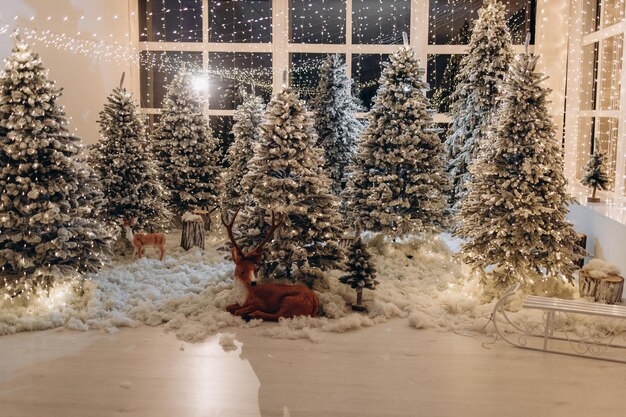 Silvester-Fotozone mit Schnee in der Nähe einer Café-Bäckerei Weihnachtsdekoration Spielzeug Weihnachtsbäume Bank Girlande leuchtende Glühbirnen festliches Stimmungsbild für Postkarte