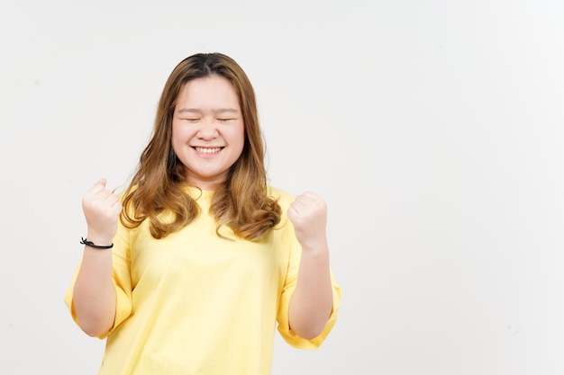 Sim gesto de celebração de linda mulher asiática vestindo camiseta amarela isolada em fundo branco