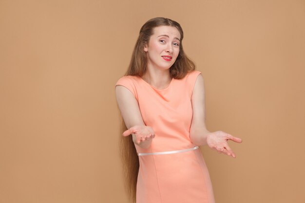 Sim, por favor, aceite. olhando para a câmera. retrato de mulher bonita, bonita emocional com maquiagem e cabelo comprido em um vestido rosa. indoor, studio shot, isolado em fundo marrom claro ou bege.