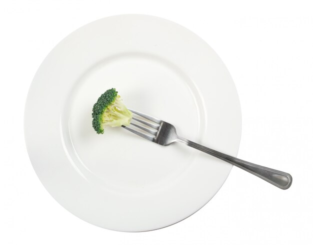 Símbolo de alimentos crudos. Florete de brócoli solitaria en un plato con un tenedor sobre fondo blanco. Fotografía de comida de vista superior