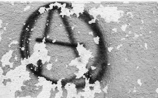 Símbolo de anarquía pintado en la vieja pared pelada
