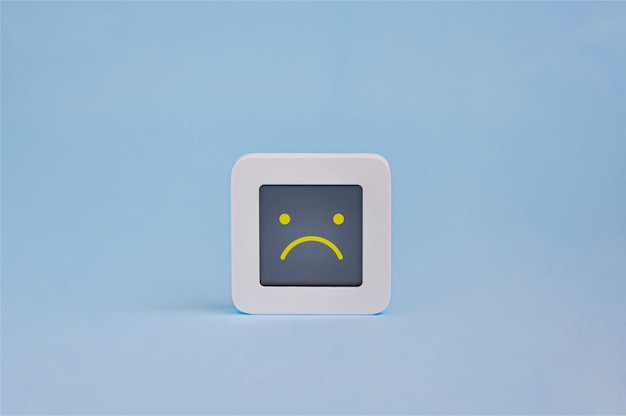 Símbolo de concepto de emoción depresiva de emoticono triste en pantalla lcd aislado sobre fondo de color Concepto de experiencia del cliente