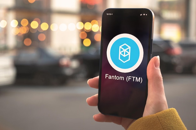 Símbolo da criptomoeda fantom ftm, logotipo. conceito de negócios e financeiro. mão com smartphone, tela com close-up do ícone de criptografia