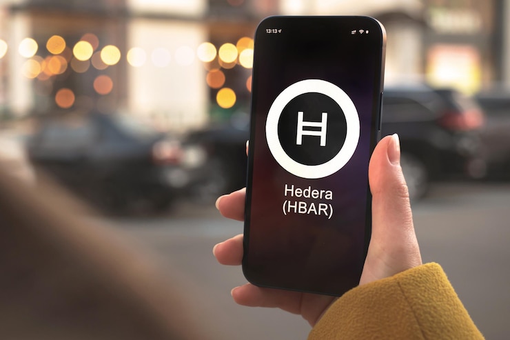 Símbolo da criptomoeda Hedera HBAR, logotipo. Conceito de negócios e financeiro. Mão com smartphone, tela com close-up do ícone de criptografia