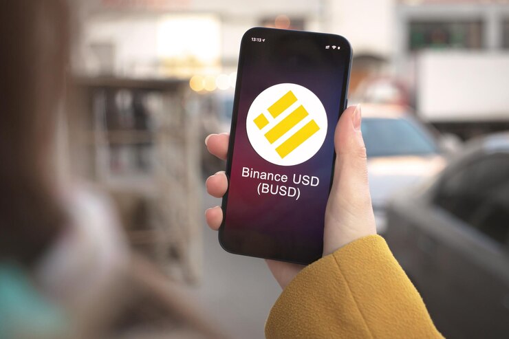 Foto símbolo de criptomoeda binance usd, logotipo busd. conceito de negócios e financeiro. mão com smartphone, tela com close-up do ícone de criptografia