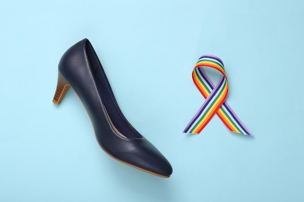 Símbolo de fita de orgulho de arco-íris LGBT e sapatos de salto alto em fundo azul Vista superior Flat lay