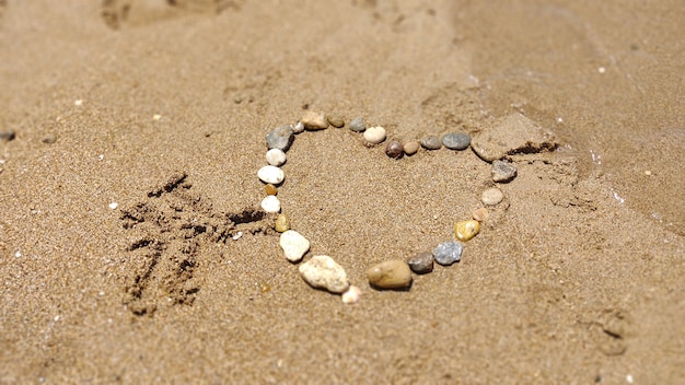 Símbolo do coração desenhando pedras na areia. Férias de verão
