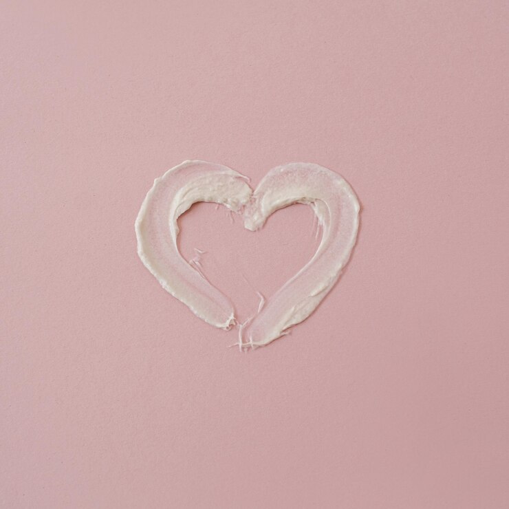 Símbolo do coração feito de mancha de creme cosmético em fundo rosa Produto cosmético de beleza estética