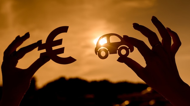 Símbolo do euro e o carro nas mãos das mulheres, contornados ao pôr do sol. Foto de alta qualidade