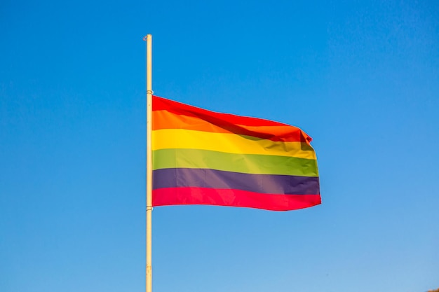 Símbolo do movimento LGBT da bandeira do arco-íris contra o fundo do céu azul