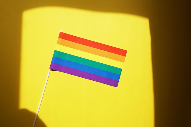 Símbolo do orgulho gay ou lgbt da bandeira do arco-íris contra um fundo amarelo com moldura de sombra