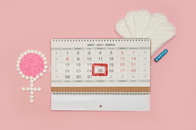 Símbolo femenino hecho de tabletas y días del período femenino del calendario menstrual o concepto de ciclo menstrual