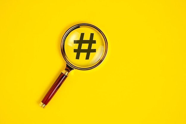 Símbolo de hashtag bajo lupa sobre fondo amarillo