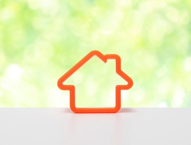 Símbolo de icono de casa naranja Icono de casa en mesa blanca con fondo verde