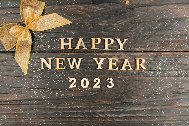 Un símbolo del número 2023 con lentejuelas doradas y lazo sobre un fondo de madera El concepto de celebrar un Feliz Año Nuevo y Navidad