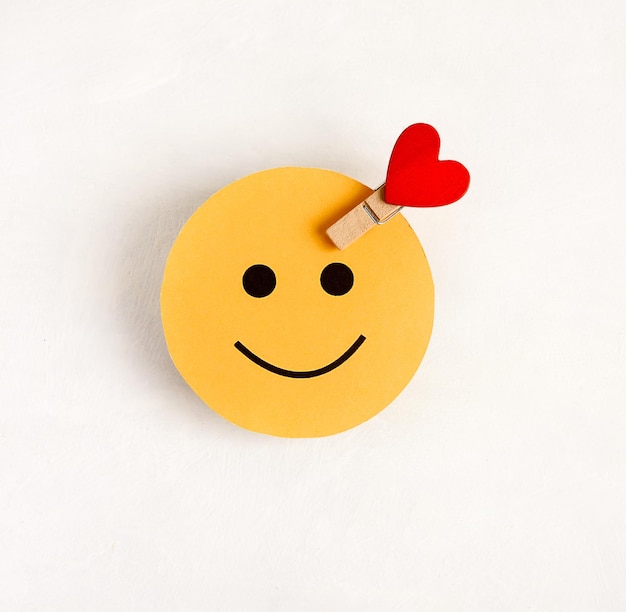 Foto el símbolo de una persona feliz es una cara redonda con un corazón sobre un fondo blanco