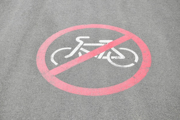 Foto símbolo prohibido andar en bicicleta en la carretera asfaltada. señal de prohibido andar en bicicleta impreso en el suelo sobre asfalto.