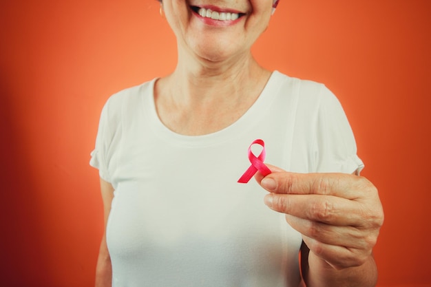 Símbolo de protección contra el cáncer de mama Mujer madura con cinta rosa y camiseta blanca aislada para la campaña contra el cáncer de mama