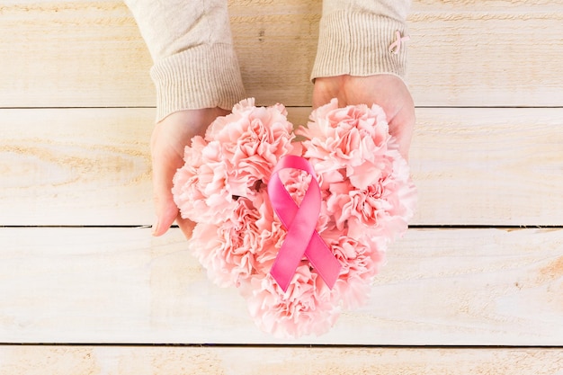 Símbolo de salud de la mujer en cinta rosa sobre tabla de madera.