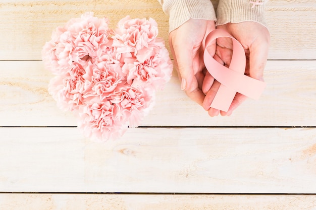 Símbolo de salud de la mujer en cinta rosa sobre tabla de madera.