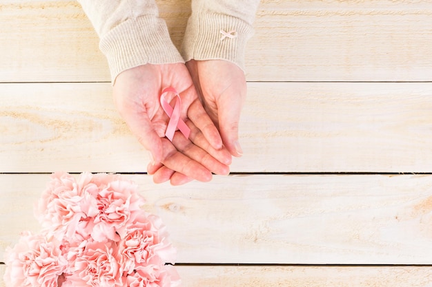 Símbolo de salud de la mujer en cinta rosa sobre tabla de madera.