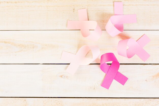 Símbolo de salud de la mujer en cinta rosa sobre tabla de madera.