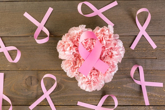 Símbolo de salud de la mujer en cinta rosa sobre tabla de madera.