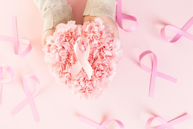 Símbolo de salud de la mujer en cinta rosa sobre tabla de madera.