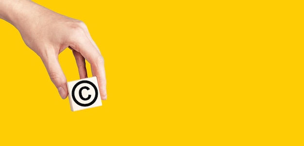 Símbolo de signo de copyright en banner de mano Ley de patentes de protección de propiedad intelectual sobre fondo amarillo