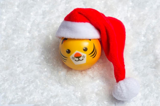 El símbolo del tigre de año nuevo con un gorro de Papá Noel en la nieve sobre un fondo de luces bokeh. Concepto de año nuevo