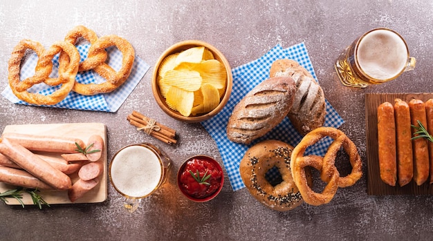 Símbolos de decoração do festival Oktoberfest feitos de batatas fritas de salsicha de cerveja Pretzel e tecido branco e azul da Baviera em fundo de pedra escuro