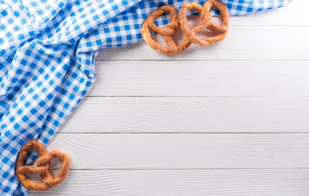 Símbolos de decoração do festival oktoberfest feitos de pão de pretzel e tecido branco e azul da baviera em fundo branco de madeira