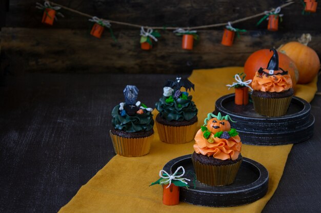 Símbolos de halloween, preparação para o feriado. cupcakes de abóbora laranja e decoração em madeira.