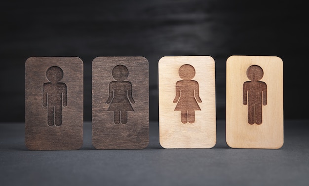 Símbolos de madeira de homens e mulheres no fundo preto.