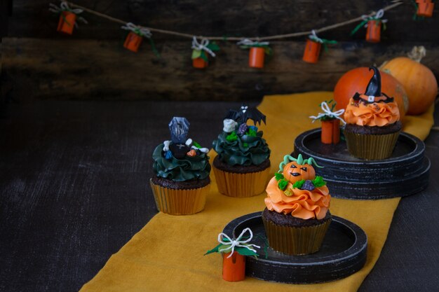 Símbolos de Halloween, preparación para las vacaciones. Cupcakes de calabaza naranja y decoración de madera.