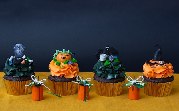 Símbolos de Halloween, preparación para las vacaciones. Cupcakes de calabaza naranja y decoración de madera.